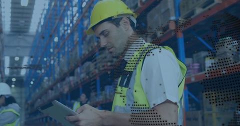 Warehouse worker checking inventory on tablet wearing hard hat and vest with digital overlay