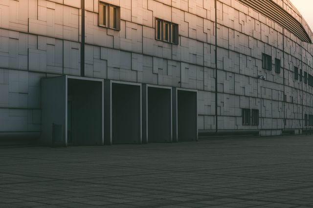 Industrial building exterior with empty storage units during sunset. The photo showcases clean lines and modern architecture with a metal facade, perfect for themes on urban life, industry, building structure, or architectural design.