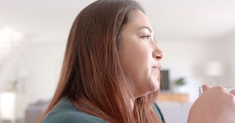 Thoughtful Woman Enjoying Tea While Working from Home