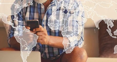 Senior man tapping smartphone with faint world map overlay representing global connectivity