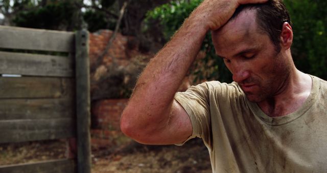 A tired man wiping sweat off his forehead, displaying signs of exhaustion after a strenuous work-related activity outdoors. Suitable for depicting themes of hard work, labor industry, summer heat, and physical exhaustion. Ideal for use in marketing materials, blog posts about working conditions, or illustrations for stories involving manual labor.