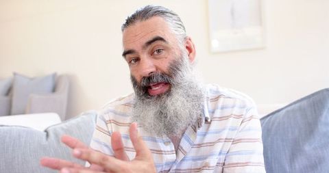 Elderly man with gray beard communicating handsomely at home