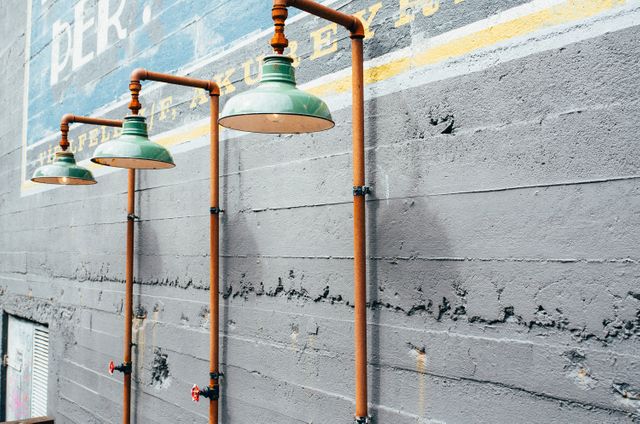 Rustic outdoor industrial lamp fixtures mounted on weathered concrete wall. Displaying urban decay and perseverance. Ideal for advertising urban living, industrial design concepts, or themes of vintage architectural exploration.