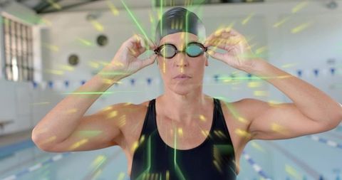 Focused mature swimmer adjusting goggles at indoor lap pool preparing for race