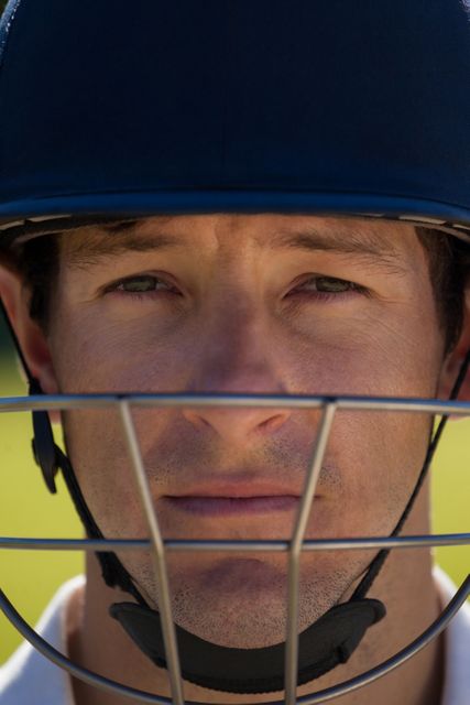 Close up view of a cricket player wearing a helmet, showing a serious and focused expression. Ideal for use in sports-related content, advertisements for cricket gear, or articles about cricket players and their dedication to the game.