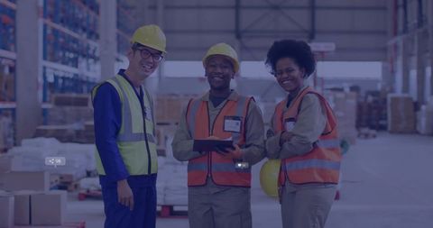Warehouse team standing in aisle wearing high-visibility vests and hard hats holding tablet