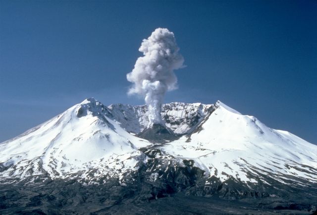 This image shows a dramatic volcanic eruption with a plume of smoke rising from the snowy peaks of a mountain. Useful for illustrating geological studies, natural disasters, volcanic activity, and Earth's natural phenomena. Ideal for educational material, science websites, and nature documentaries.