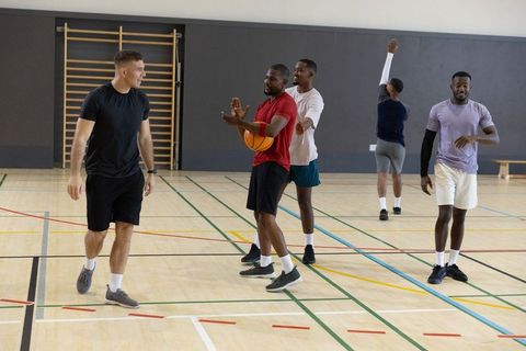 Group of men playing pickup basketball practicing defense and passing on indoor gym court
