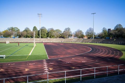 Empty outdoor running track surrounding football field under clear blue sky