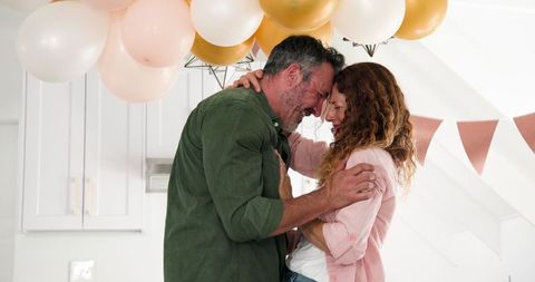 Happy Couple Embracing Under Decorated Balloons at Home Celebration