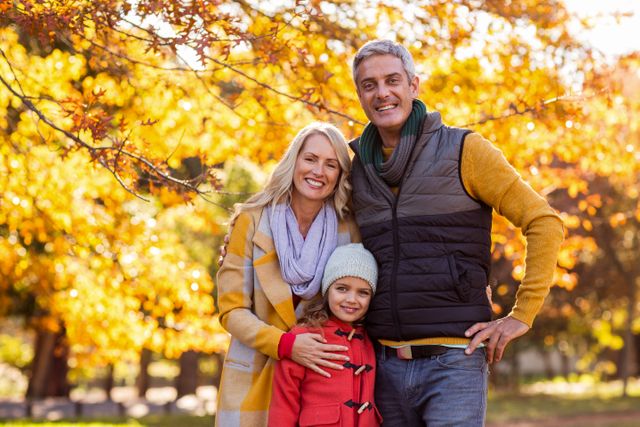 Portrait of happy family standing against trees at park during autumn