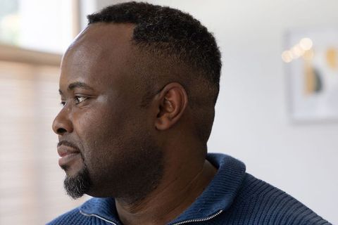 African american man gazing in natural light wearing blue knit zip sweater contemplative headshot