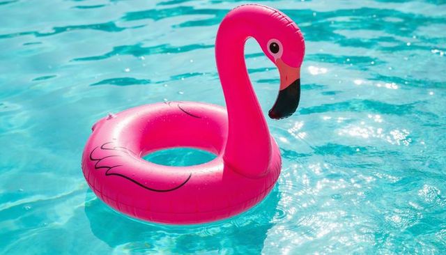 Bright pink flamingo pool float drifting on sparkling turquoise water