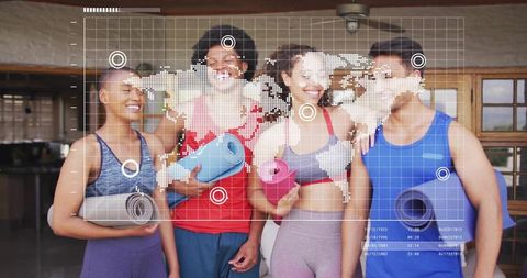 Smiling fitness group holding rolled yoga mats with digital world map hud overlay