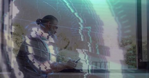 Bearded man scrolling smartphone at window with glitchy cyan digital overlay