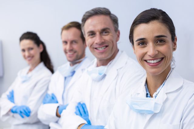 Group of dentists standing together in a dental clinic, smiling confidently with arms crossed. Ideal for use in healthcare, dental care, and medical team-related content. Perfect for promoting dental services, teamwork in healthcare, and professional medical staff.
