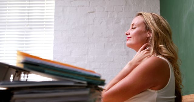 Casual businesswoman rubbing her neck in the office - Download Free Stock Photos Pikwizard.com