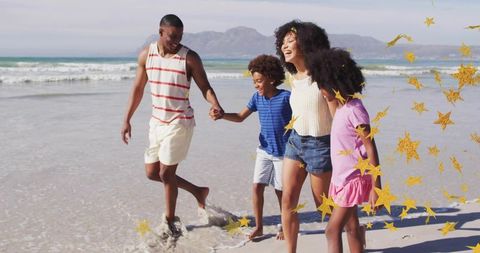 Joyful family walking and splashing on sunlit beach with golden confetti celebration