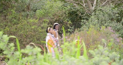 African American Couple Walking Through Wildflower Meadow and Woodland Wearing Scarves