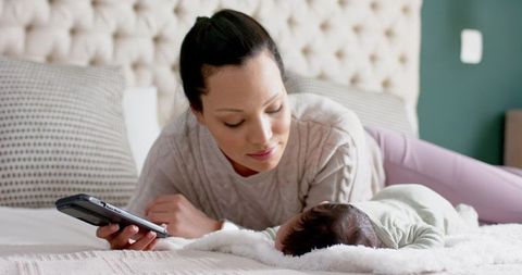 Mother Bonding with Sleeeping Baby on Bed Using Tablet