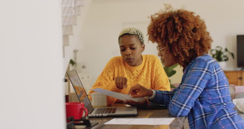 Diverse Couple Collaborating on Laptop With Documents at Home