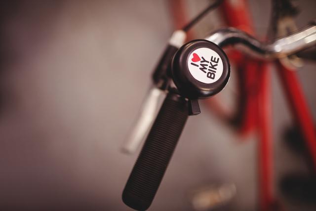 This image captures a close-up view of a bicycle bell with an 'I Love My Bike' sticker attached to the handlebar. Ideal for use in cycling-related articles, bike maintenance guides, or promotional materials for bike accessories. The image conveys a sense of personal attachment to cycling and can be used to highlight the importance of bike safety and accessories.