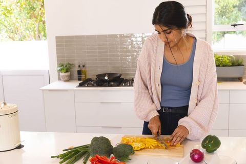 Woman chopping vegetables in modern kitchen with natural light