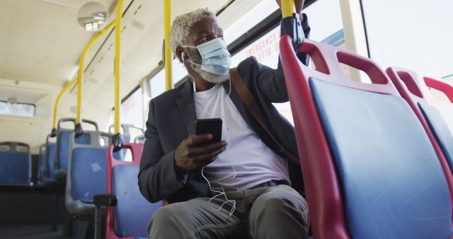 African american senior man wearing face mask using smartphone while sitting in the bus - Download Free Stock Photos Pikwizard.com