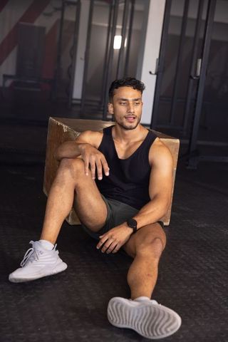 Fit asian man resting after workout leaning on plyometric box showing strength and endurance