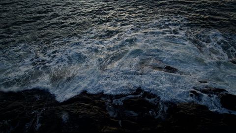 Dark Ocean Waves Crashing Over Rocky Shore at Dusk Aerial View Moody Surf