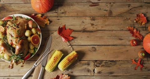 Rustic thanksgiving feast with roasted turkey, corn and pumpkins on farmhouse table