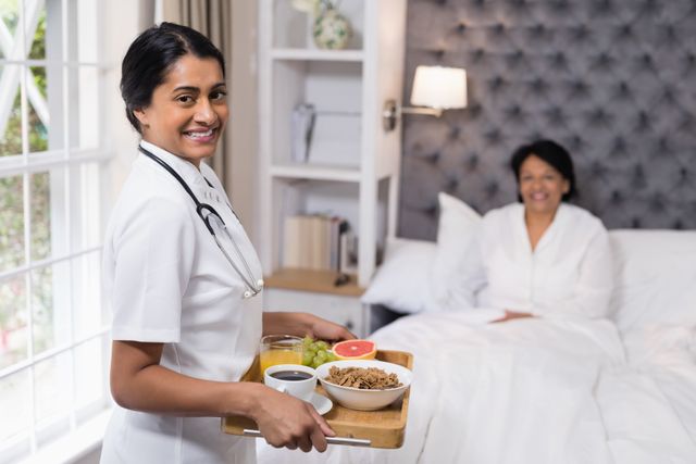 Portrait of nurse serving breakfast to patient resting on bed at home