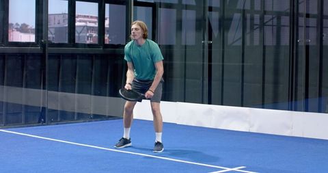 Male athlete preparing with paddle on indoor blue sports court