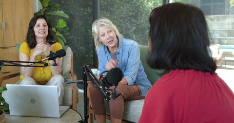 Three women recording relaxed podcast with senior guest in cozy home studio