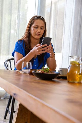 Asian Woman Relaxing in Cafe Checking Smartphone