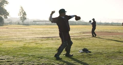 Baseball teammates throwing at sunrise with gear