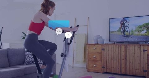 Woman on exercise bike engaging in virtual workout session at home