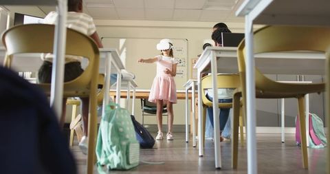 Elementary girl wearing vr headset engaging in virtual lesson while classmates watch