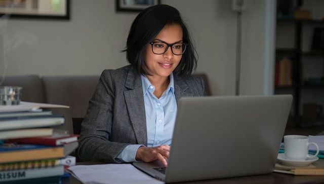 Professional Woman Typing at Workspace with Laptop and Books