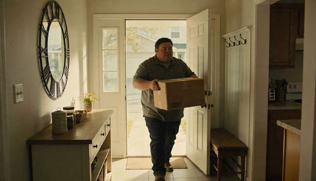 Man carrying cardboard box into bright home foyer residential delivery and welcoming arrival