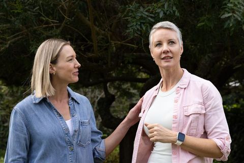Adult daughter supporting senior woman during garden stroll, showing companionship and care