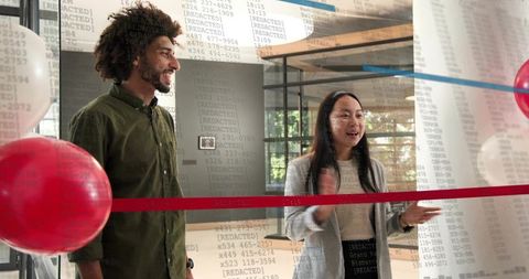 Smiling team celebrating ribbon cutting in modern glass lobby for launch and collaboration
