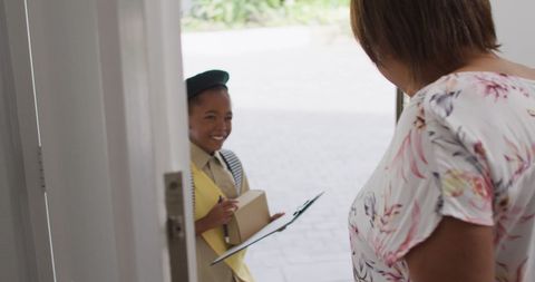 Smiling girl scout delivering package to welcoming woman
