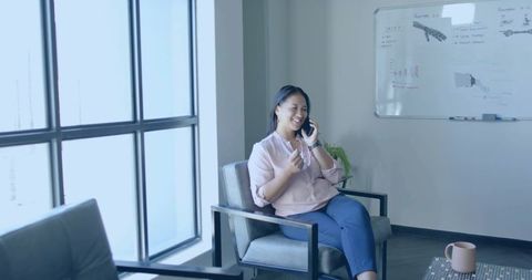 Asian Woman Talking on Smartphone in Office Lounge