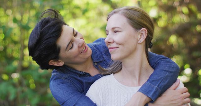 Two women embracing and smiling in an outdoor setting, showing love and happiness. Perfect for themes like LGBTQ+ relationships, affection, love, inclusivity, and outdoor connection. Useful in articles, ads, or brochures related to diversity, romance, and equality.
