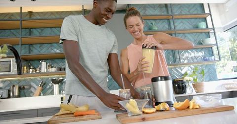 Happy Diverse Couple Making Smoothie in Modern Kitchen