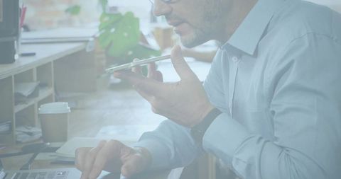 Businessman engaged in phone conversation typing on laptop