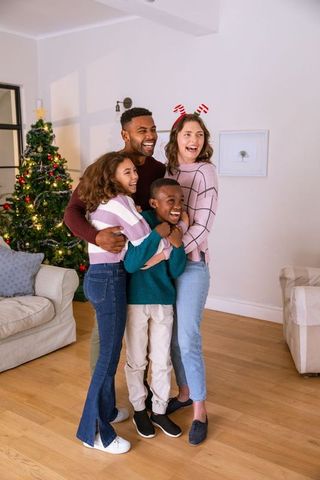 Diverse Family Embracing in Cozy Living Room Next to Christmas Tree