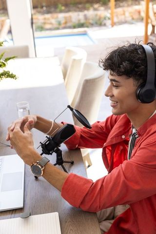 Young man podcasting with microphone and laptop
