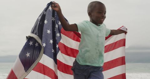 Joyful Child Running with American Flag on Beach